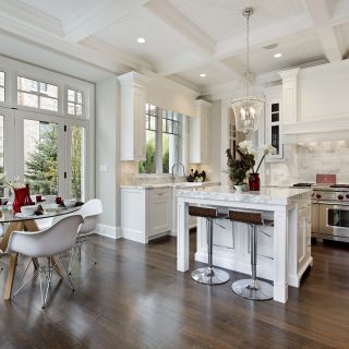 A clean white kitchen that has bright lighting and open large windows
