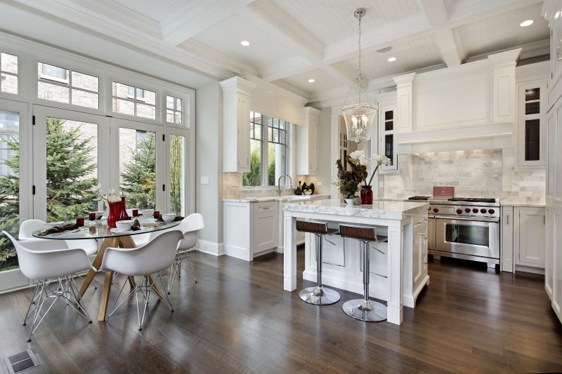 A clean white kitchen that has bright lighting and open large windows